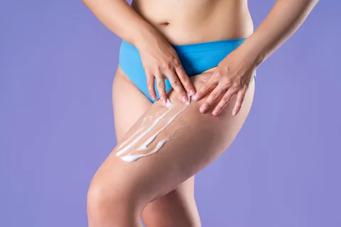 Jeune femme qui applique de la crème sur ses jambes