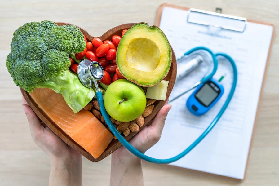 Un bol de fruits et légumes formant un coeur à côté d'un stéthoscope