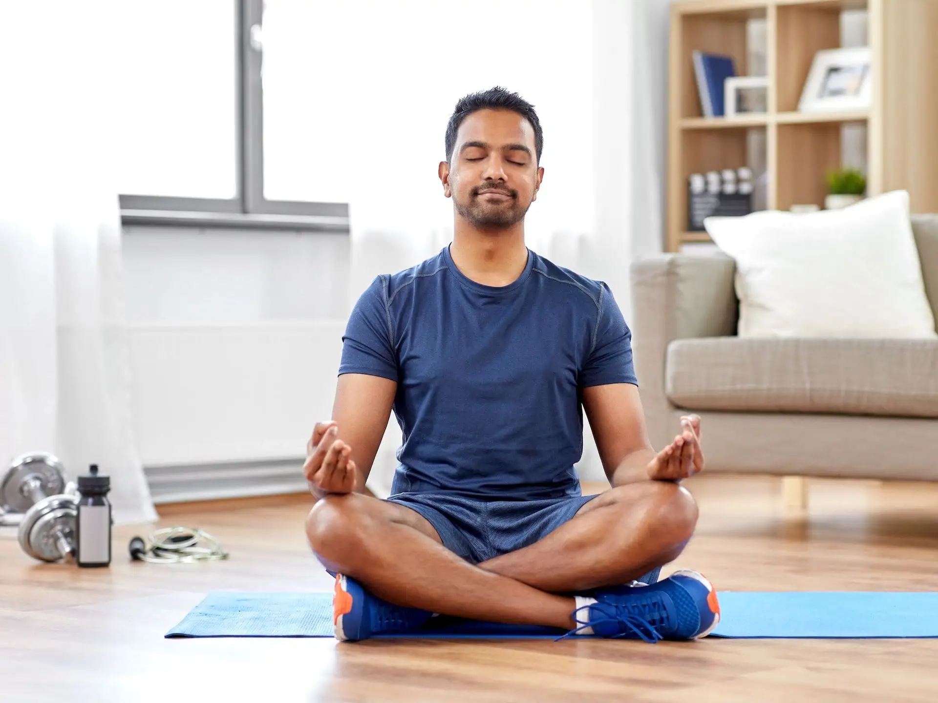 Homme en position de méditation dans son salon