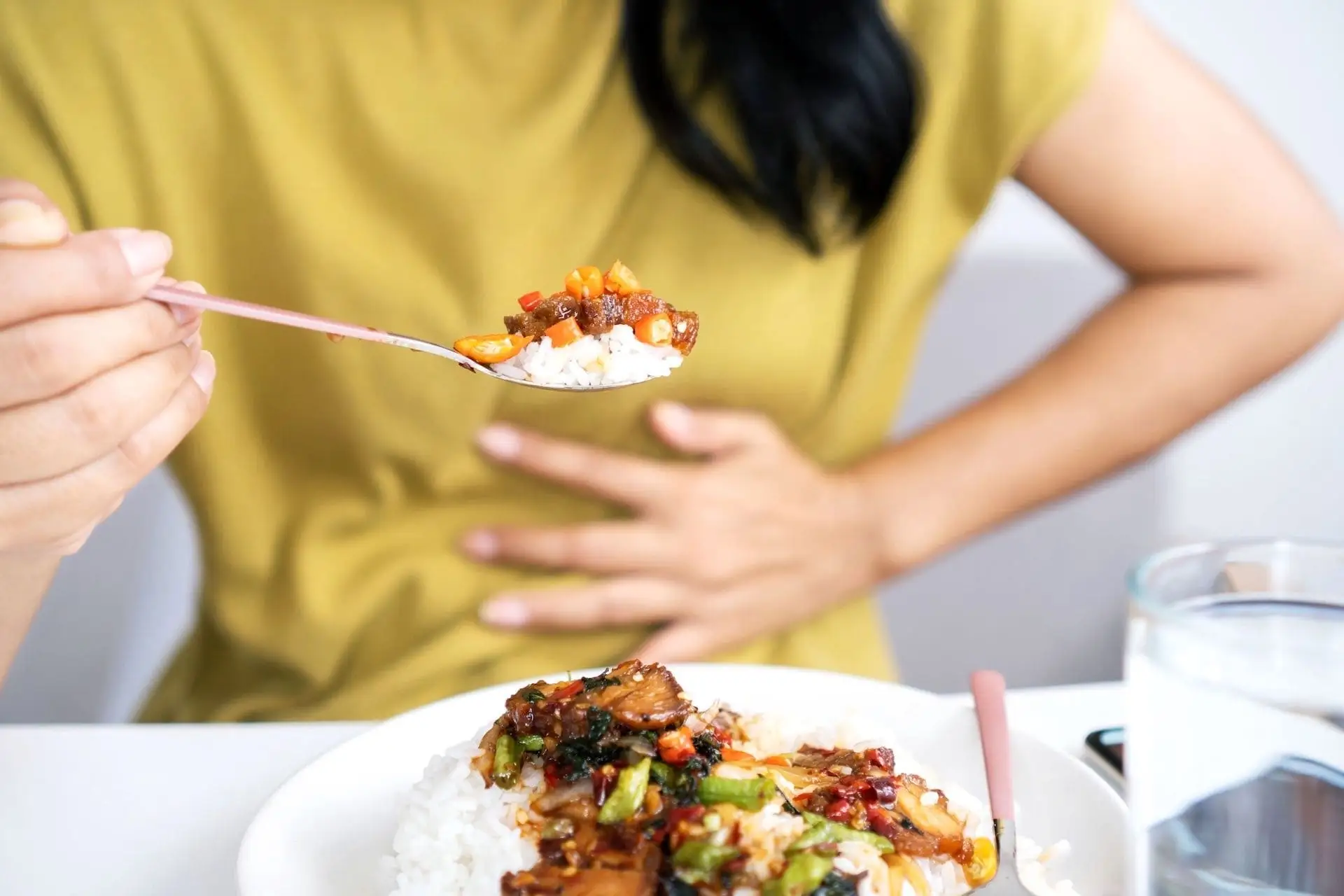 Femme qui mange en se tenant le ventre