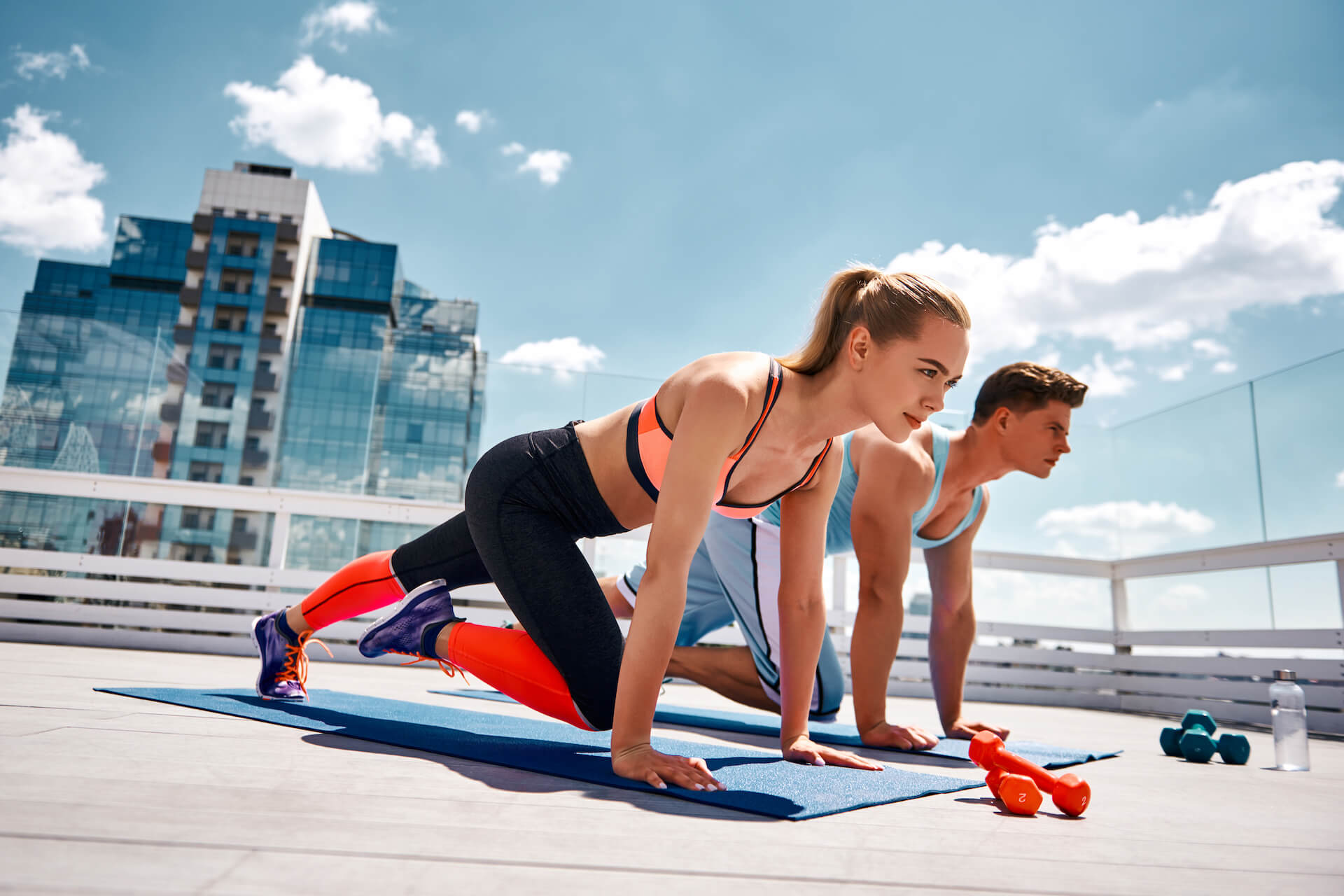 Couple réalisant des exercices d'abdominaux sur un toit d'immeuble