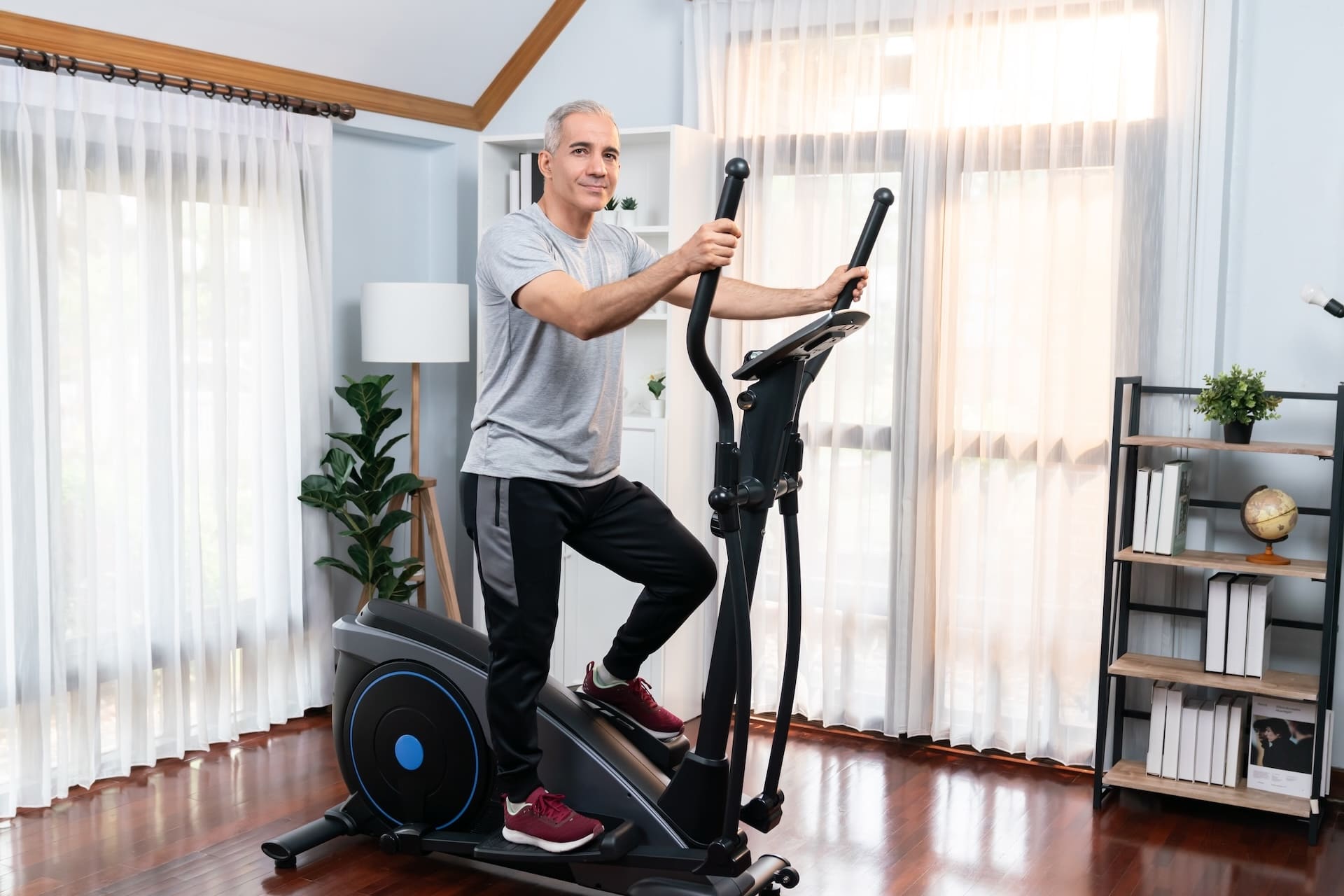 Homme âgé sur un vélo elliptique dans son salon